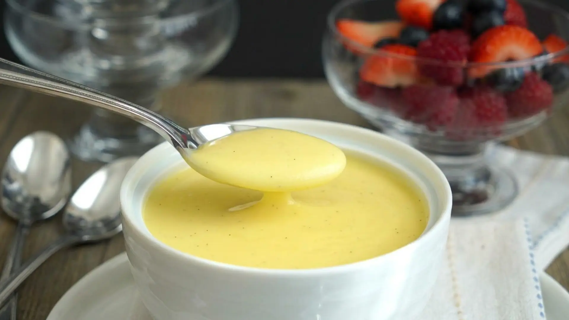 smooth homemade vanilla custard in a white bowl on a wooden surface
