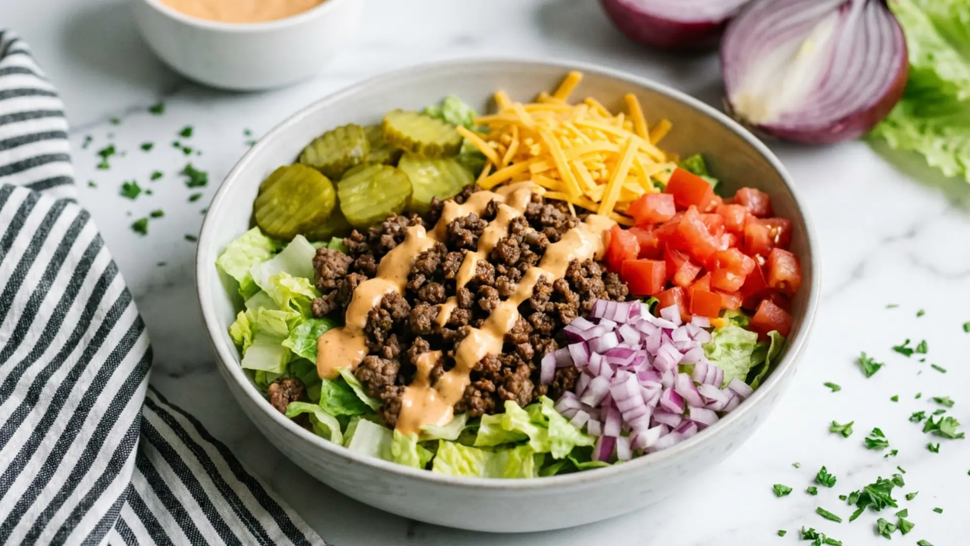 big mac salad recipe with seasoned ground beef cheddar pickles tomatoes and creamy special sauce in a white bowl