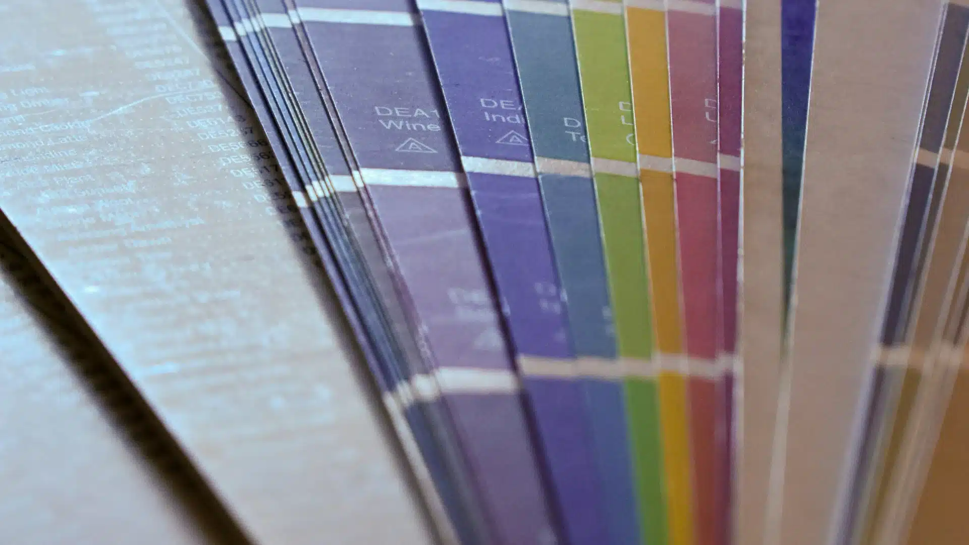Close-up of paint color swatch fan deck showing multiple interior paint samples in blues, greens, yellows and neutrals