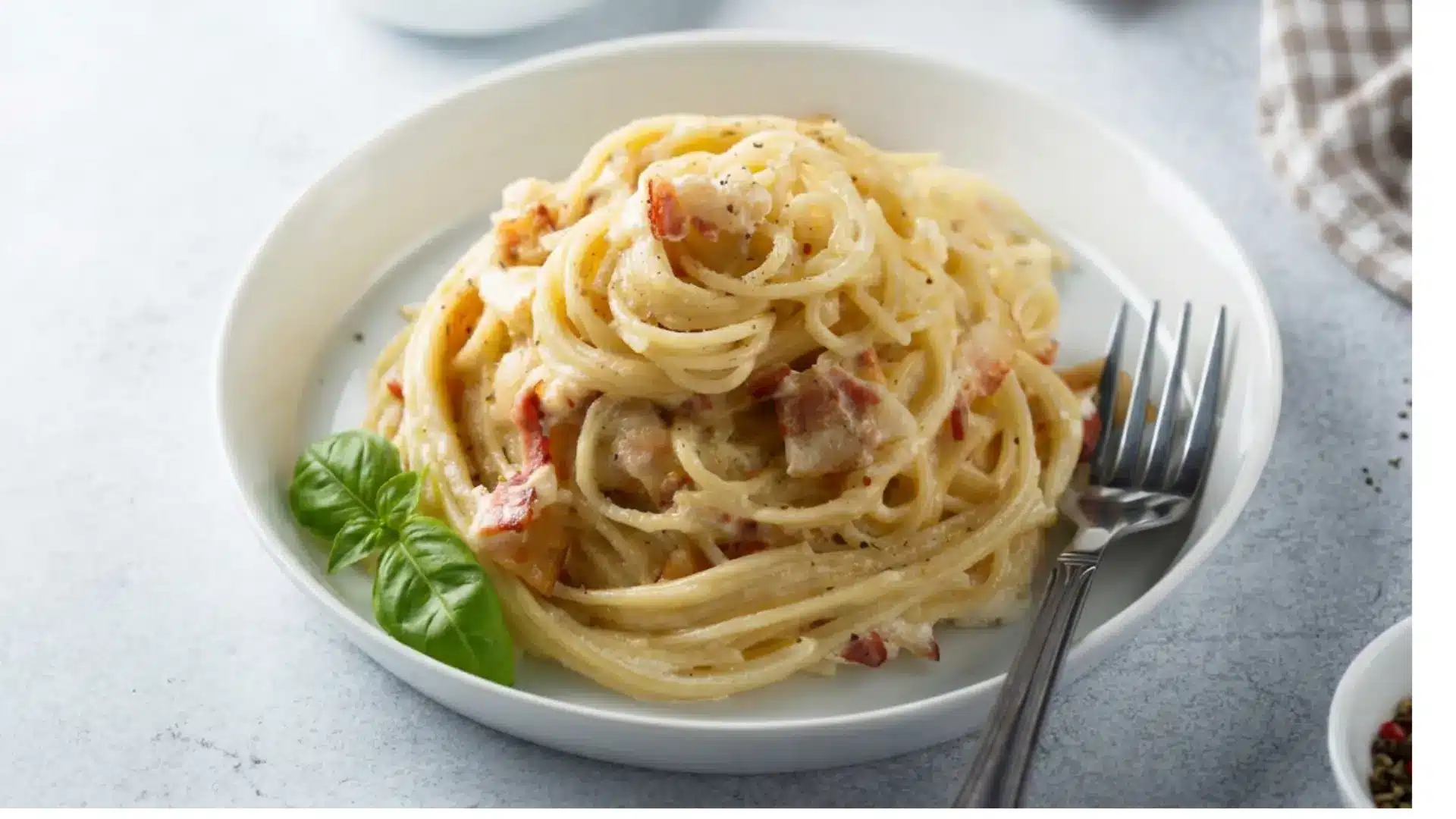 spaghetti carbonara with egg yolk sauce pancetta and black pepper in a bowl