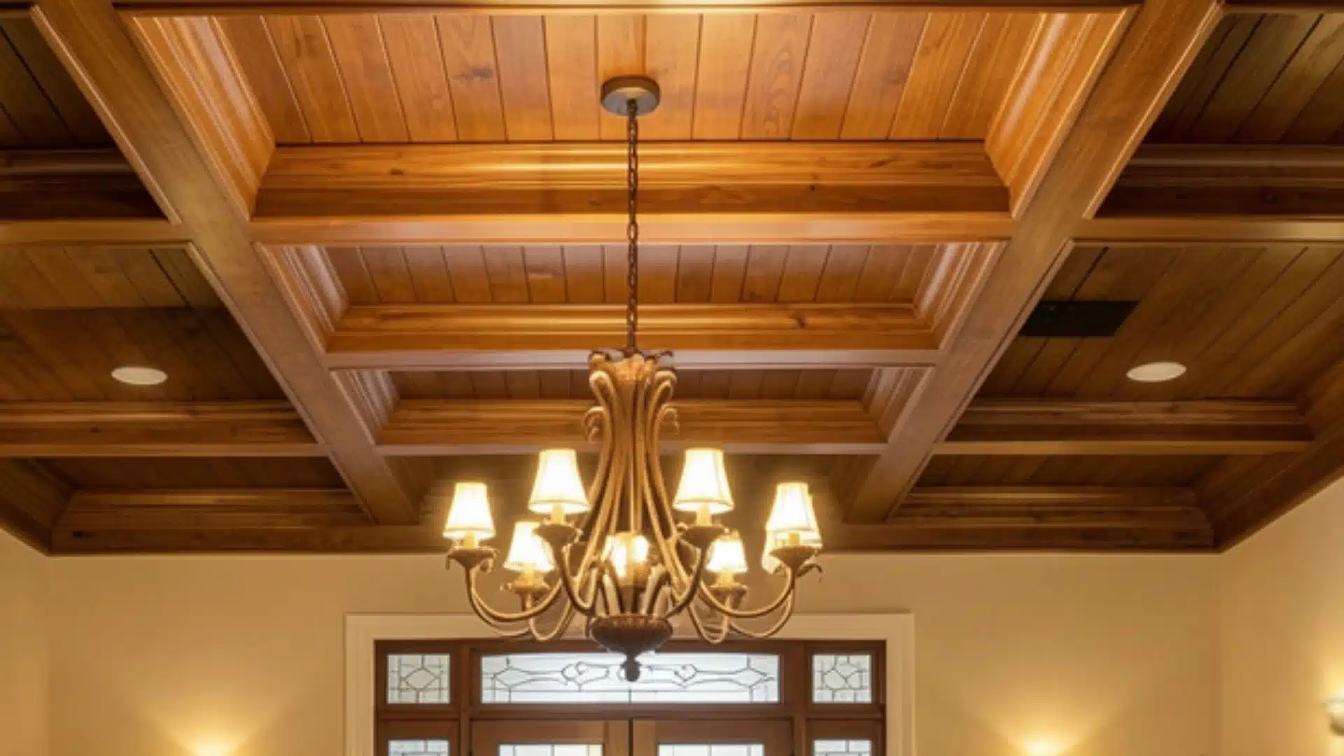 A spacious room featuring a wooden ceiling and an elegant chandelier hanging from it.