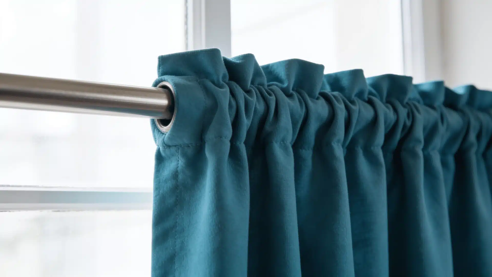 Close-up of teal rod pocket curtains gathered softly on a metal curtain rod