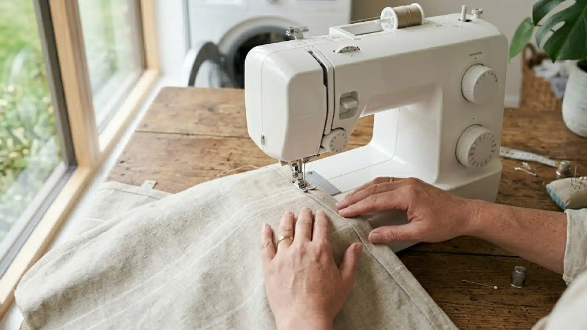 Hands marking fabric on wooden table with ruler and chalk for curtain measurements DIY sewing process