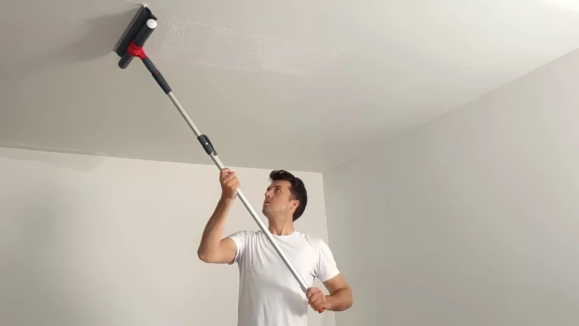 Man using an extension pole with a roller to texture a ceiling