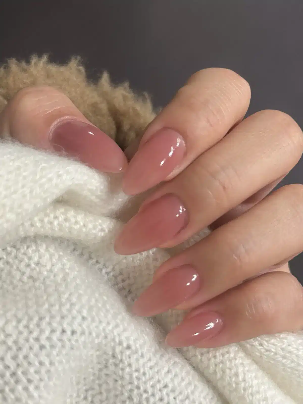 Close up of glazed donut nails in sheer pink nude on almond shape with high gloss finish by Nails by Gleidy