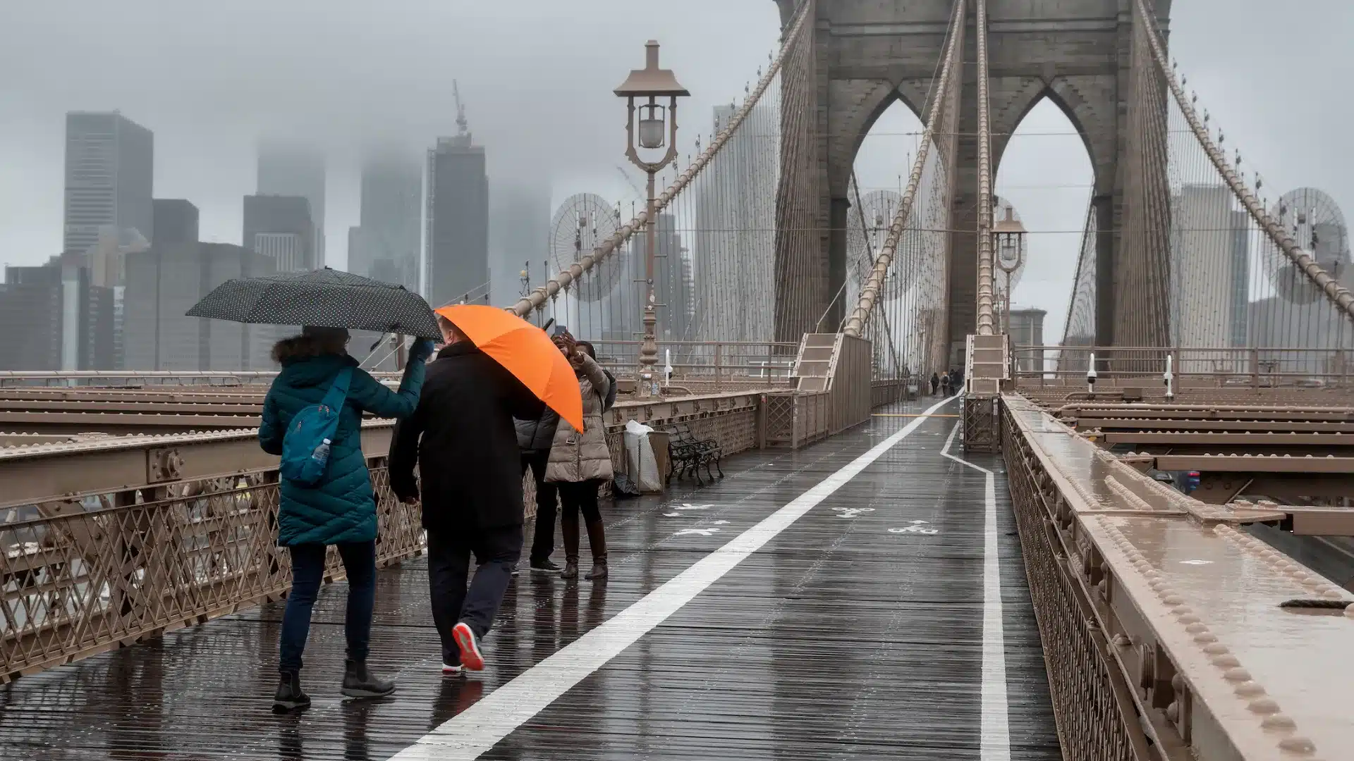 A group of people walking across a bridge, enjoying the view and the outdoors.