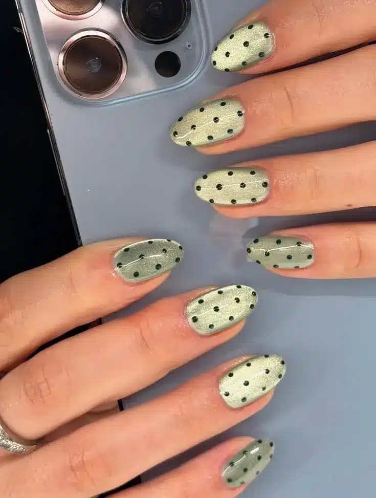 Tiny black dot accent nails on pale green oval shape minimalist nail art