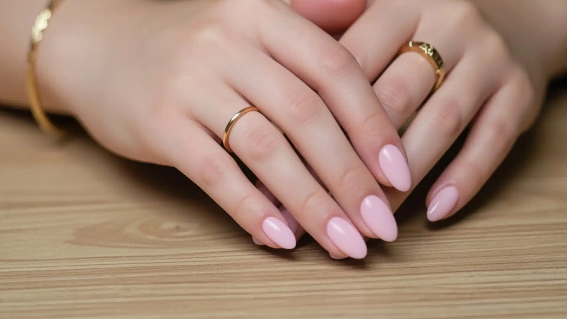 A detailed view of a woman's hands featuring neatly manicured pink nails, highlighting elegance and grooming.