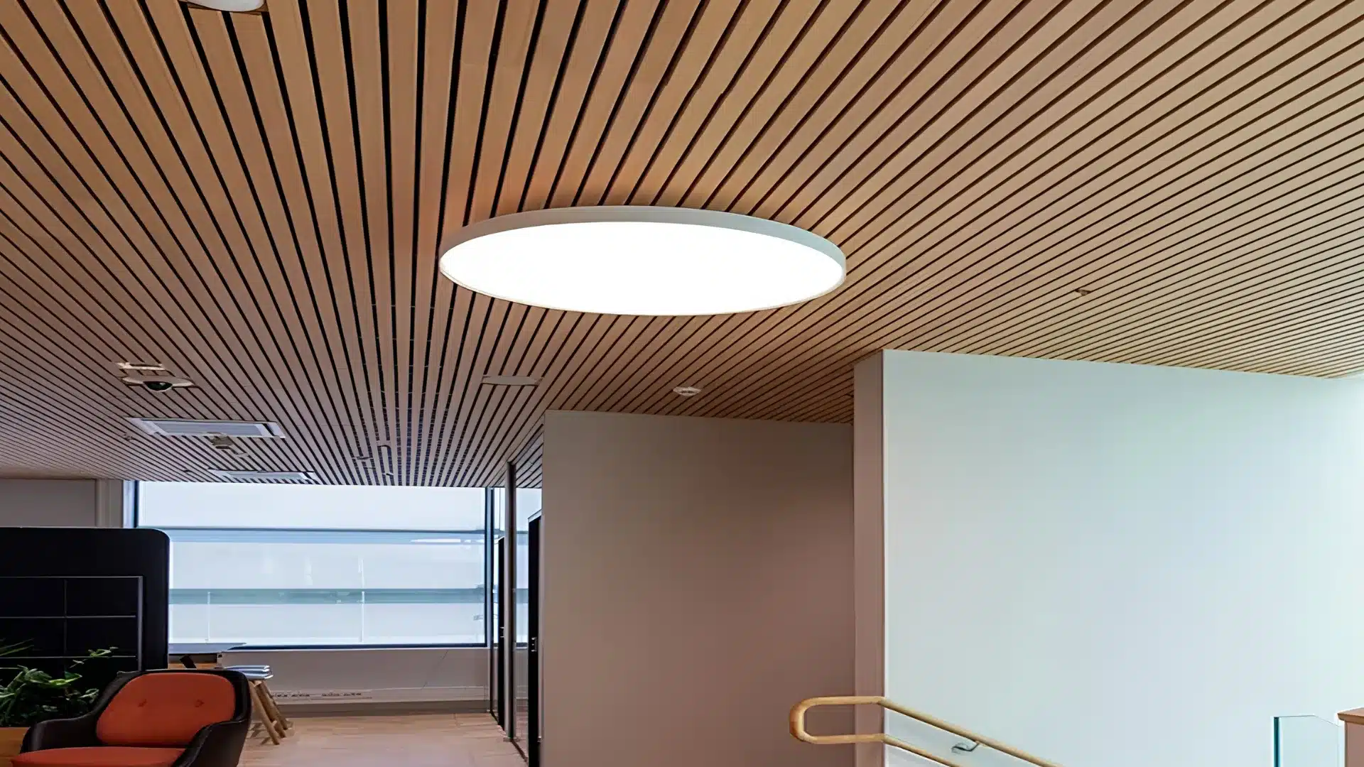 Modern interior with a slatted wood ceiling, circular ceiling light, and a window with blinds