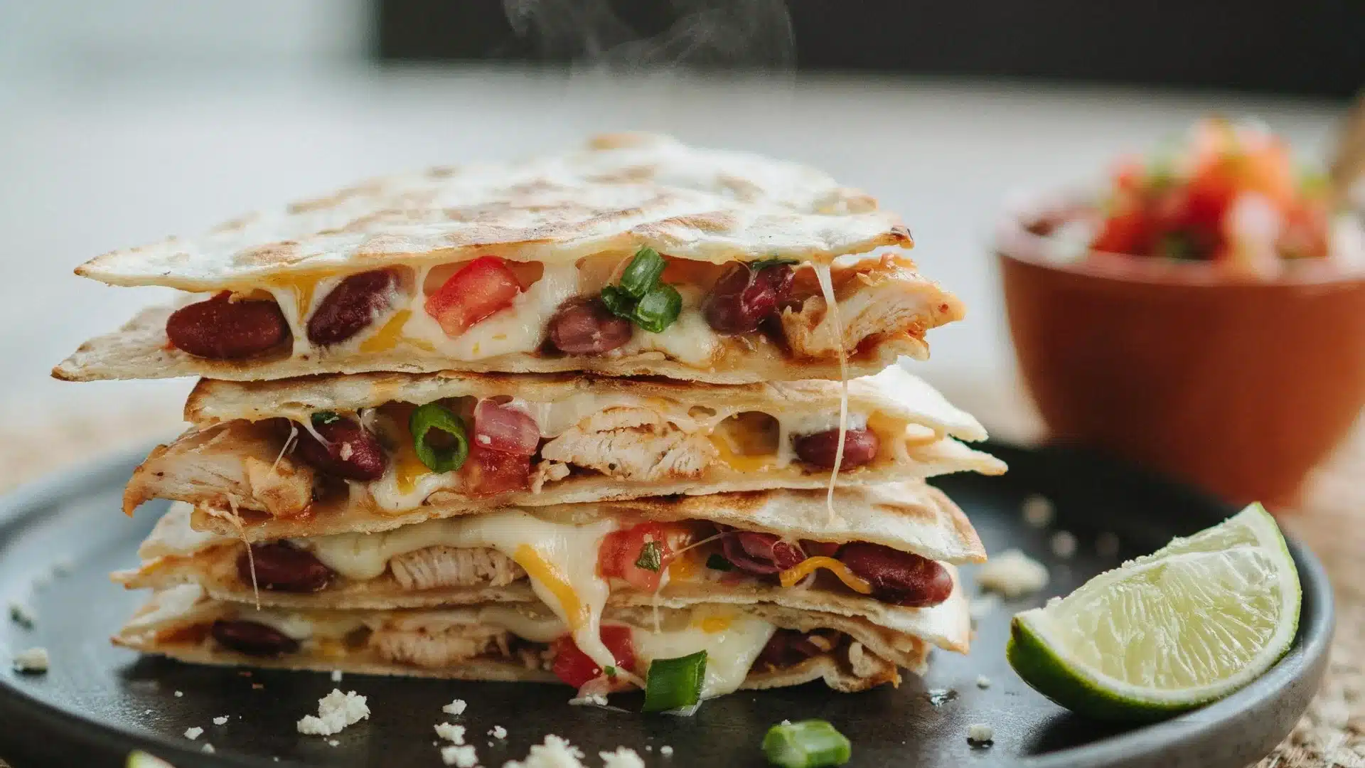 A close-up of a stack of quesadillas, showcasing layers of cheese, chicken, and peppers, arranged neatly on a plate.