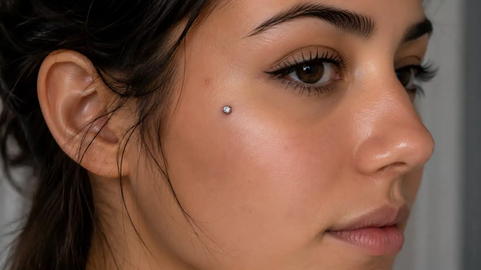 A woman with a cheekbone piercing, showcasing her cheekbone and facial features in a close-up view.
