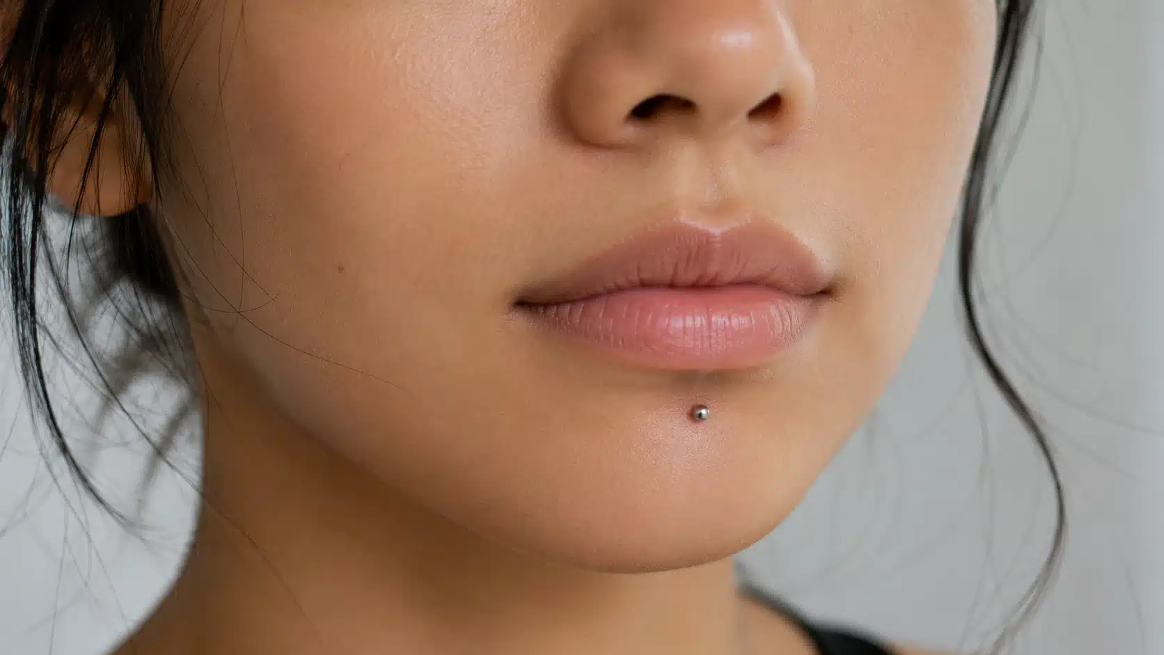 Close-up of a woman's face featuring a prominent chin piercing.