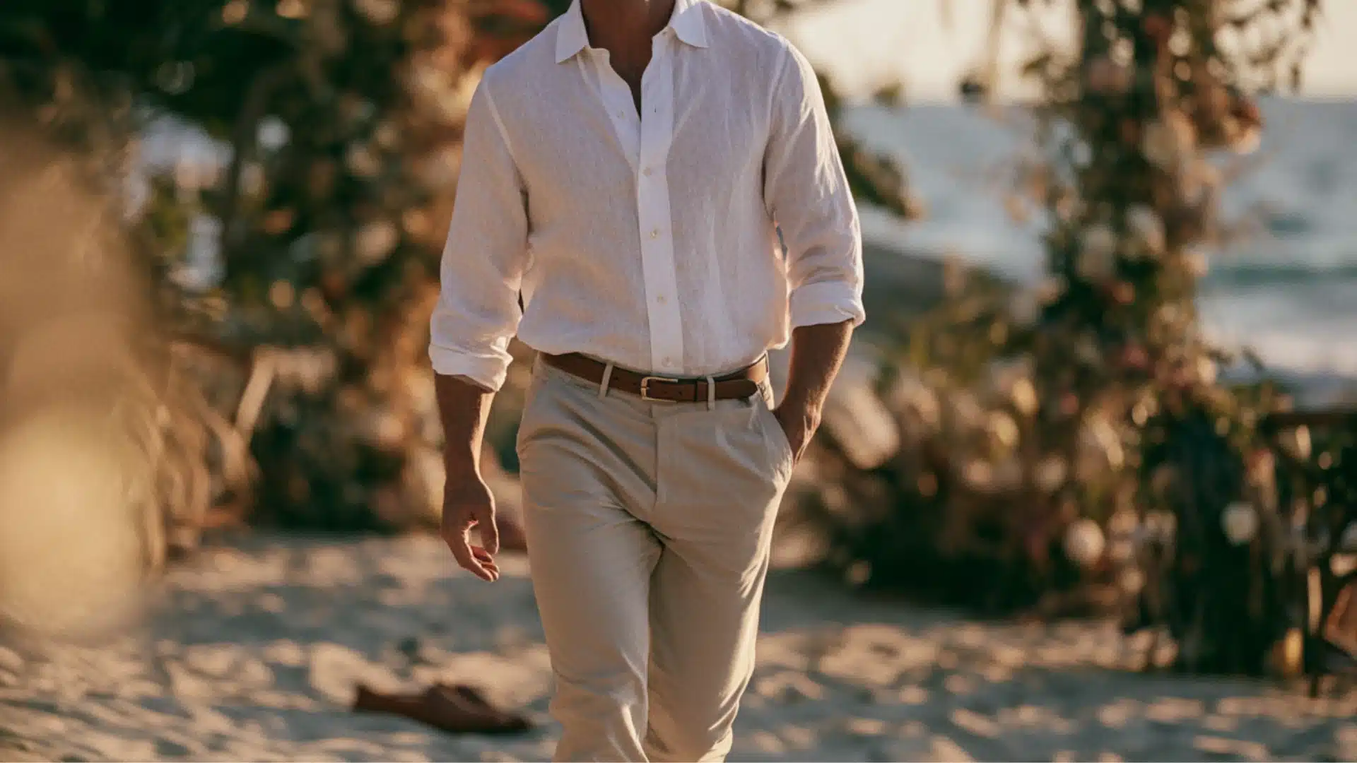 man wearing a white linen shirt with rolled sleeves and beige chinos at a casual beach wedding venue
