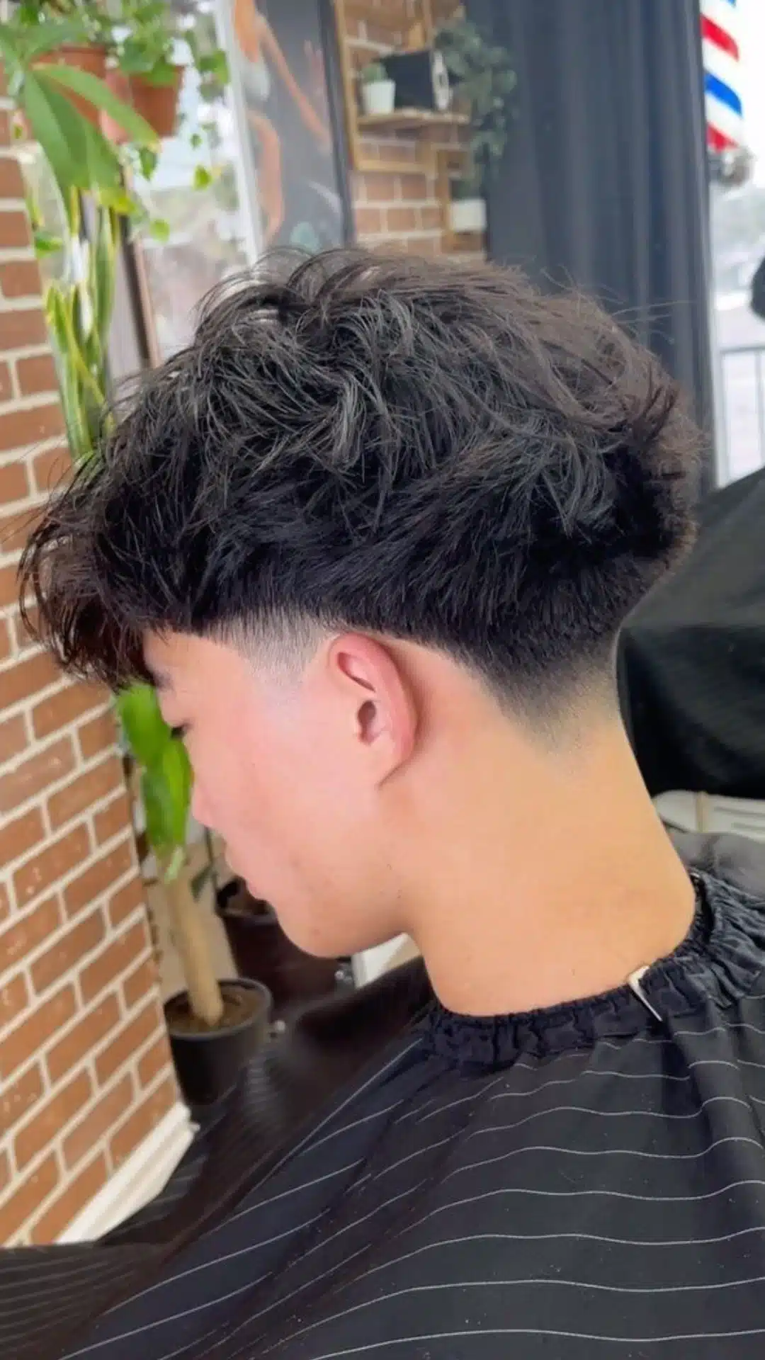 Side and back view of a man with a taper haircut and textured fringe featuring a soft gradual taper around the sides and neckline