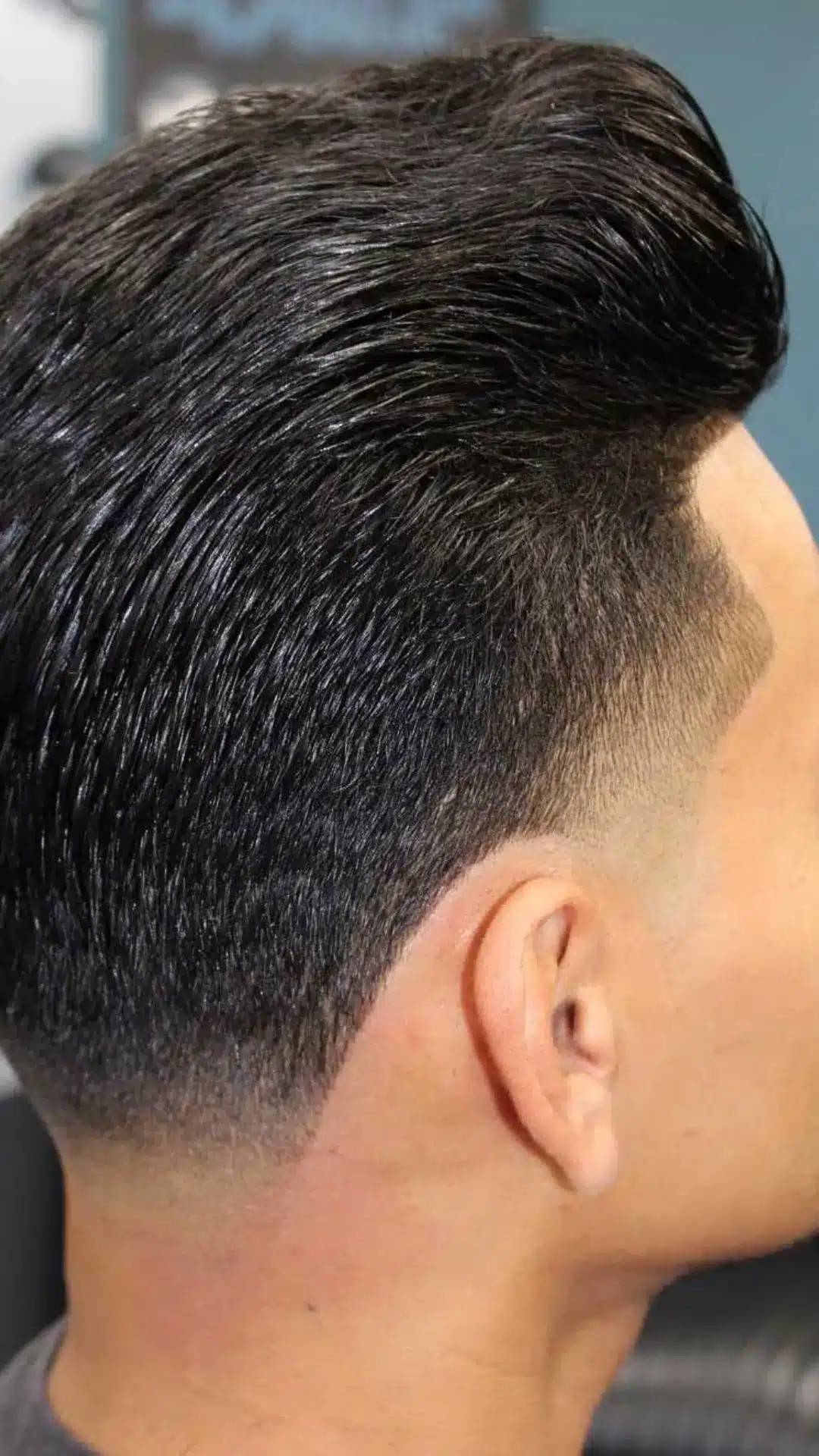 Side profile of a man with a pompadour taper haircut featuring voluminous swept back hair