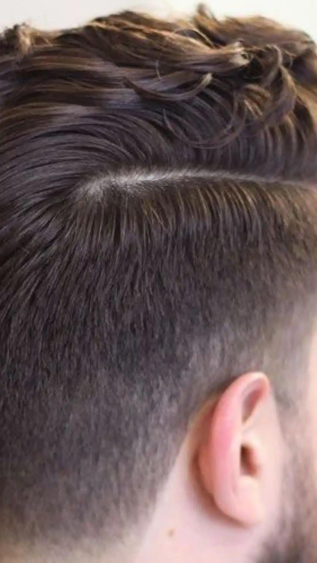 Side profile of a man with a side part taper haircut featuring a defined part